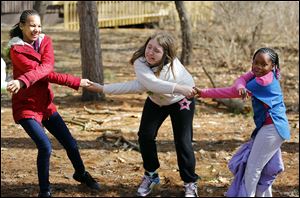 Chloe Bowling, 10, Lia Smith, 10, and Nyomi Bell, 7, from left, have fun as they form the Girl Scout’s Friendship Circle during a Spring Break Day Camp at Camp Miakonda in Sylvania.