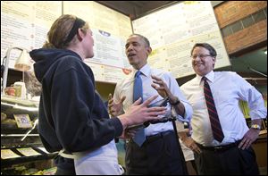 President Obama, accompanied by Rep. Gary Peters (D., Bloomfield Hills, Mich.), right, talks with employee Andrea Byl to order lunch during their visit to Zingerman’s Deli in Ann Arbor. After eating his Reuben sandwich on Wednesday, the President traveled to the University of Michigan to speak about his proposal to raise the national minimum wage.