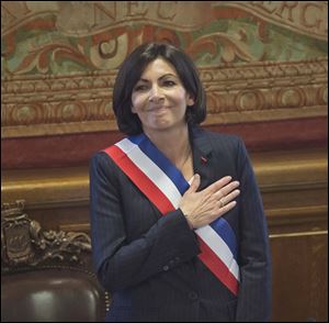 The new mayor of Paris Anne Hidalgo, wearing the mayoral sash in the color of the French Republic, acknowledges applause after her election today in Paris.