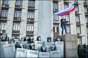 An activist waves a Russian national flag above Ukrainian police at the regional administration building in Donetsk, Ukraine, on Sunday. Protest leaders want lawmakers to discuss a vote on joining Russia.
