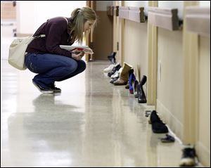 Stephanie Simon, a nursing student at Owens Community College, kneels along a path of shoes — a visual path for healing and education —at Mercy College in Toledo. The shoes belong to victims of suicide. Mercy hosted the ‘Step Up. Stop Suicide’ event to increase awareness in Northwest Ohio. 