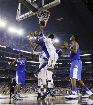 Kentucky guard James Young (1) dunks between Connecticut forward DeAndre Daniels (2) and center Amida Brimah (35) during the second half.