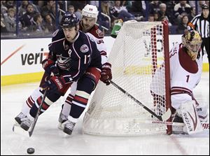 Columbus Blue Jackets' Brandon Dubinsky, left, carries the puck behind the net as Phoenix Coyotes' Antoine Vermette, center, defends and Thomas Greiss, of Germany, protects the net during the second period.