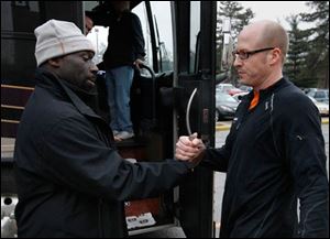 Lourdes University men's basketball coach Andre Smith, left, says goodbye to head volleyball coach Greg Reitz as the volleyball team boards the bus.