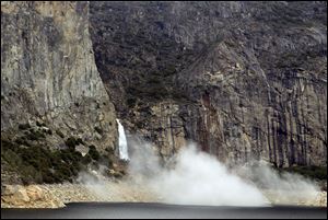 In this photo supplied by Yosemite National Park, dust rises from a rockfall on March 31. Officials say approximately 16,000 tons of rock fell 500 feet from a cliff near Hetch Hetchy Reservoir. 
