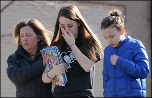 A parent escorts distraught students from Franklin Regional Senior High School, where 21 students and a security guard were injured during a Wednesday attack by a 16-year-old with two 8-inch steel knives.