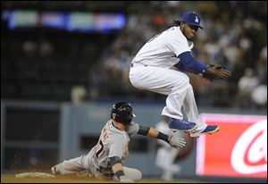 Los Angeles Dodgers shortstop Hanley Ramirez, right, jumps to avoid Detroit Tigers' Andrew Romine, left, after he threw to first to complete a double play during the eighth inning.