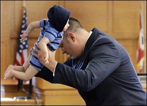 Frank Spryszak, an assistant Lucas County prosecutor, demon-strates to the court with a doll how 6-month-old Avery Bacon suffered the injuries that caused his death in December, 2012.