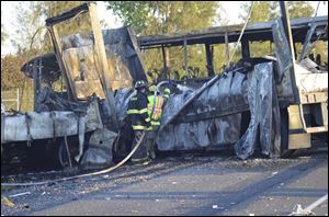 Firefighters hose down the wreckage of a bus and a semitruck that collided Thursday just north of Orland, Calif., that left at least nine dead.