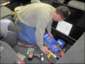 Tom Vatalaro of Vic's Sports Center in Kent, Ohio, installs batteries in the boat of Toledo professional angler Ross Roberston as the craft is prepped for the 2014 season.