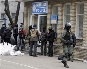 Armed pro-Russian activists occupying the police station carry riot shields today in the eastern Ukraine town of Slovyansk.