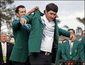 Defending Masters champion Adam Scott helps Bubba Watson on with the traditional green jacket given to winners of the tournament. Watson also won the tournament in 2012.