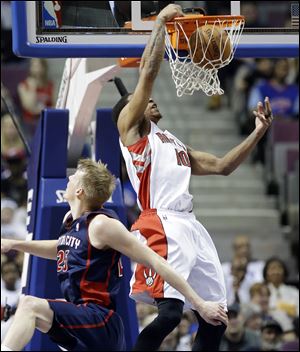 Toronto Raptors guard DeMar DeRozan dunks while defended by Detroit Pistons forward Kyle Singler during the first half Sunday in Auburn Hills, Mich.