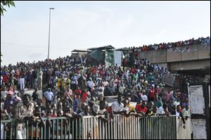 People gathered at the scene of an explosion at a bus park in Abuja, Nigeria, today.  An explosion blasted through a busy commuter bus station on the outskirts of Nigeria's capital, Abuja, before 7 a.m. as hundreds of people were traveling to work.