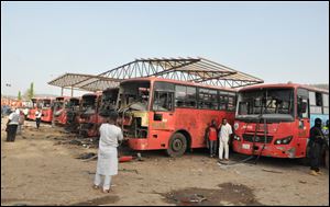 Onlookers inspect damaged buses following an explosion at a bus park in Abuja, Nigeria, today.