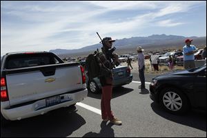 Tyler Lewis, from St. George, Utah, stands in the middle of north bound I-15 with his gun near Bunkerville, Nev. while gathering with other supporters of the Bundy family.