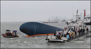 South Korean Coast Guard officers try to rescue missing passengers from a sunken ferry in the water off the southern coast near Jindo, South Korea, Thursday0
