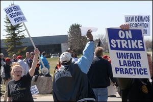Amanda Dickerson, left, raises her picket sign high as she and other Piston Automotive employees, along with existing union members and supporters, strike.Rausch