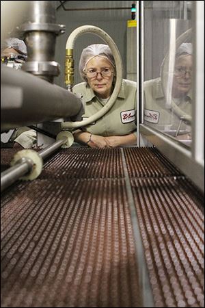 Debra Gonzalez, who has worked at Blommer Chocolate for 17 years, inspects chocolate chips as they are dropped onto a conveyor belt and sent through a cooling chamber.
