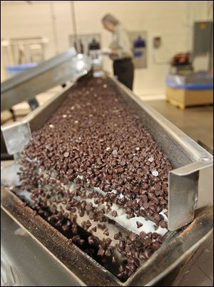 Thousands of chocolate chips fall off the conveyor belt and into a hopper. Companywide, Blommer processes nearly 200,000 metric tons of cocoa beans a year.