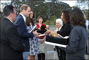 Britain's Prince William, second left, and his wife, Kate, the Duchess of Cambridge, third left, are given a gift by Aboriginal elders Chris Tobin, right, Aunty Sharon Brown, and Aunty Sharon Halls, third left, while on a tour of Echo Point with Randall Walker, left, CEO of Blue Mountains Lithgow and Oberon Tourism, and Anthea Hammon, center, Joint Managing Director of Scenic World in Katoomba, Australia.