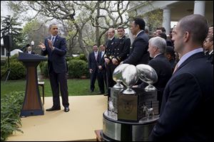 President Barack Obama applauds as he presents the Commander-in-Chief's Trophy to the United States Naval Academy football team today during a ceremony in the Rose Garden of the White House in Washington.