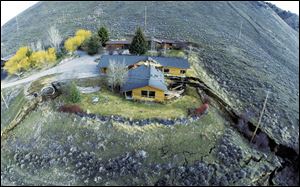 This aerial image provided by Tributary Environmental shows a home damaged by a landslide Friday in Jackson, Wyo.