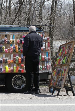 Bill McMath of Ferndale, Mich., looks over the selection of fishing lures that Clarence Labiche has for sale along the Maumee River.