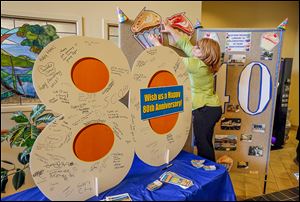 Jodi Russ, community librarian at the Bedford Branch Library puts up an 80th anniversary display for the Monroe County Library System. The Bedford branch has been on Jackman Road 40 years.