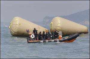 South Korean rescue team members work to rescue passengers believed to have been trapped in the sunken ferry Sewol near the buoys which were installed to mark the vessel in the water off the southern coast near Jindo, south of Seoul, South Korea, today.