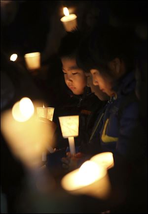 Kindergartens hold candles Sunday as they pray for safe return of passengers of the sunken ferry Sewol, in Ansan, South Korea.