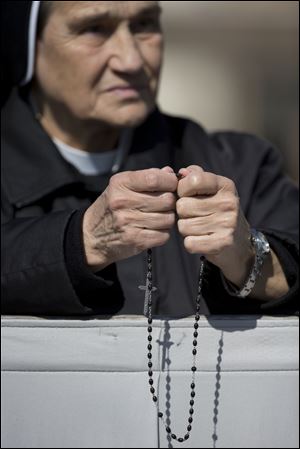 A nun holds a rosary as she prays prior to the arrival of Pope Francis to celebrate an Easter Sunday Mass.