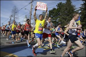 Runners in the first wave of 9,000 cross the start line of the 118th Boston Marathon today in Hopkinton, Mass.