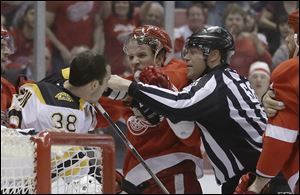 A referee breaks up Boston Bruins left wing Jordan Caron (38) and Detroit Red Wings left wing Justin Abdelkader during the first period.