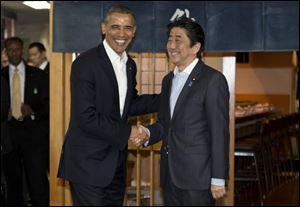 President Barack Obama and Japanese Prime Minister Shinzo Abe shake hands before having dinner at Sukiyabashi Jiro sushi restaurant in Tokyo today.