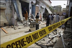 Pakistani security officials inspect the site of a bomb attack in Karachi today.