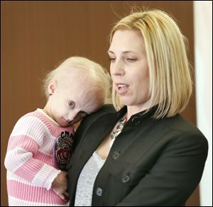 Carly Kudzia, 3, held by her mother, Heather, is the 2014 Children’s Miracle Network Hospitals champion for Ohio. Carly, who will be 4 on June 19, has progeria, a very rare, fatal, genetic condition characterized by accelerated aging. Her mother says it reminds them to enjoy every minute they get.