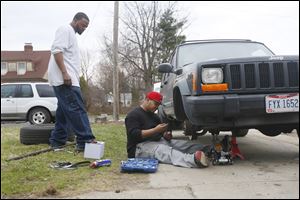 Aaron Belton, left, and his brother Chris Belton, work on fixing  Chris Belton’s vehicle in front of their house. Aaron, 27, once involved with the Lil Heads gang, has pushed himself away from the streets. Chris, 25, wrote and produced the rap song ‘My City.’ He and his manager plan to release the album next month.
