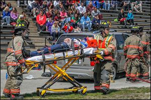 Firefighters take away an injured student during a mock-car accident at Rossford High School. Last week’s grisly exercise at the stadium aimed to teach young people the dangers of driving impaired.