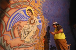 Jill Eide from EverGreene Architectural Arts, restores a piece of the mural inside St. Aloysius Catholic Church. The restoration project is expected to cost $190,000 and will be finished in a few weeks.