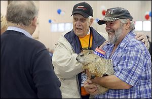 Navy veteran Harold Mucci, who fought in the Korean War, and Charlie Hoag, right, who is holding his woodchuck, HuckyToo, speak with well-wishers before Mr. Mucci boards the Honor Flight.