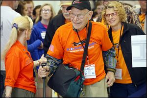 Veteran Paul Meyer is guided through the gate Wednesday by Beth Emery, Honor Flight of Northwest Ohio organizer, left, while boarding the Honor Flight at the Grand Aire hangar at Toledo Express Airport. Following behind him at right is Mr. Meyer’s guardian, Angela King.
