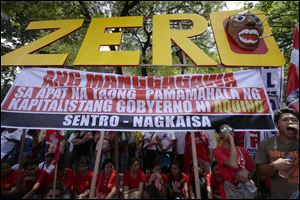 Workers shout slogans as they hold a rally near the Presidential Palace to mark the Labor Day celebrations today in Manila, Philippines. Various labor groups nationwide held protests, mostly to demand wage hikes, better working conditions and an end to corruption in the government. The sign reads: Workers Have Zero Benefits In The Four Years of Capitalist Government of Aquino. 