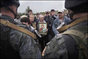 A pro-Russia demonstrator holds an Orthodox painting in front of Ukrainian Army soldiers while blocking the road Friday in Andreevka, Ukraine.  Russia has massed tens of thousands of troops in areas near the border.  