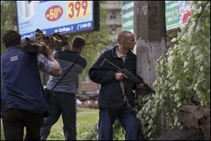 A Pro-Russian gunman holds a weapon as other activists carry a tree trunk to barricades in Slovyansk, eastern Ukraine, today.