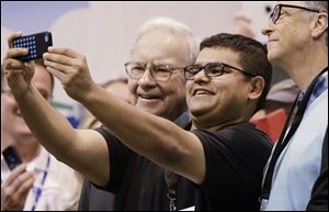 An unidentified shareholder takes a selfie with Berkshire Hathaway Chairman and CEO Warren Buffett, left, and Berkshire board member Bill Gates, right.