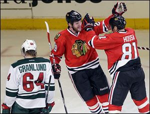 Chicago’s Bryan Bickell, center, celebrates with Marian Hossa after scoring a goal against Minnesota.