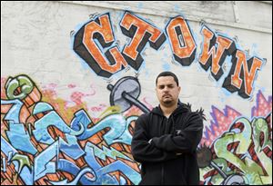 Angel Arroyo standing in front of a graffiti covered wall in Cleveland. Arroyo and the father of Gina DeJesus, who was freed in May 2013 after 10 years of captivity by Ariel Castro, went to door-to-door last summer after a young woman went missing in a neighboring city.