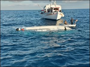 Local fishermen look a yacht used to transport immigrants illegally that overturned in a fatal accident near the Greek island of Samos today.