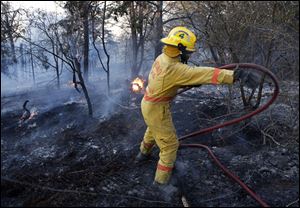 An Edmond firefighter moves a hose while battling a fire at 1600 E Forrest Hills during Oklahoma wildfires in south Logan County, Sunday.